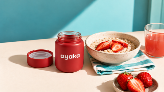 An open Ayaka jar on the breakfast table next to a bowl of strawberry porridge and a glass of juice